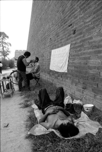 1989年，西安城墙下的牙医和光着膀子躺地休息的男子。图／fotoe 胡武功